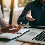 Geschäftsleute sitzen vor einem Laptop und gestikulieren