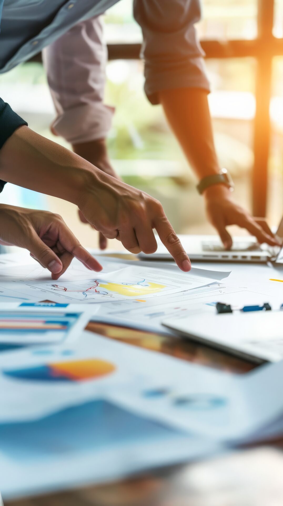 Menschen diskutieren über Unterlagen die auf einem Schreibtisch liegen